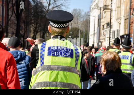 Cardiff, Wales - 2022. März: Rückansicht eines Polizeibeamten, der in einer Menschenmenge im Stadtzentrum von Cardiff im Einsatz ist Stockfoto