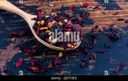 Holzlöffel mit getrocknetem Blumentee auf einem alten Holzhintergrund Nahaufnahme Stockfoto