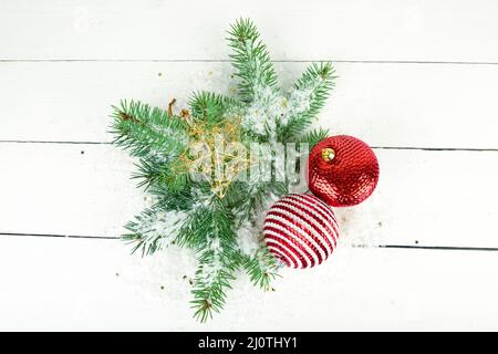 Schmuck zu Weihnachten oder Neujahr. Tannenzweigen und helle Dekorationen auf einer weißen Holzoberfläche. Stockfoto