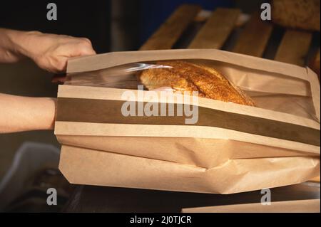 Ein Laib weißen handgemachten heißen Brotes in einem Papierbeutel mit transparenten Einsätzen auf weißem Hintergrund. Gesunde Ernährung. Hausgemachte natürliche Stockfoto