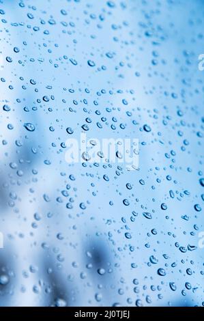 Vertikale Aufnahme. Geringe Tiefenschärfe Wassertröpfchen auf Glas bei Regenwetter mit Schlafbereichen in der Kleinstadt im Th Stockfoto