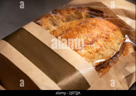 Ein Laib weißen handgemachten heißen Brotes in einem Papierbeutel mit transparenten Einsätzen auf weißem Hintergrund. Gesunde Ernährung. Hausgemachte natürliche Stockfoto