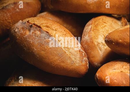 Nahaufnahme von Sauerteig-Brot. Frisch gebackenes Brot mit goldener Kruste auf den Holzregalen der Bäckerei. Der Kontext einer Germa Stockfoto