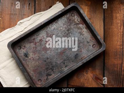 Leeres rechteckiges, rostiges Blech auf einem braunen Holztisch, Draufsicht Stockfoto