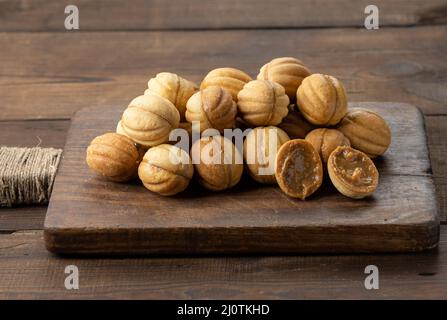 Gebackene Dessertnüsse mit Kondensmilch auf einem Holzbrett, Draufsicht Stockfoto