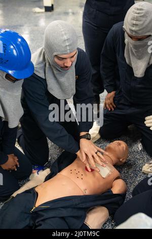 Hospital Corpsman 1. Class Travis Rister, Zentrum, aus Southgate, Michigan, zugewiesen an die medizinische Abteilung von USS Gerald R. Ford (CVN 78), gibt Anweisungen über die ordnungsgemäße Herzdruckmassage während eines simulierten medizinischen Notfalls zur Unterstützung der Phase-III-Crew-Zertifizierung, 26. Januar 2022. Die Phase-III-Crew-Zertifizierung konzentriert sich darauf, wie die Trainingsteams des Schiffes die erforderliche Crew-Schulung durchführen, die erforderlich ist, um das Schiff wieder auf See zu bringen. Ford ist im Hafen von Newport News Shipyard und führt ihre geplante inkrementelle Verfügbarkeit (PIA) durch, eine sechsmonatige Modernisierungs-, Wartungs- und Reparaturperiode. ( US Navy Foto von M Stockfoto