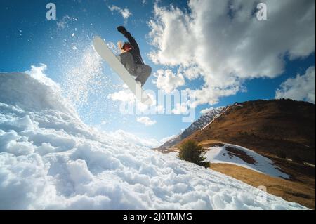 Extremer Wintersport. Junge professionelle Snowboarderin fährt eine Halfpipe. Springt von einem Halfpipe-Trampolin in der Sonne, perfo Stockfoto