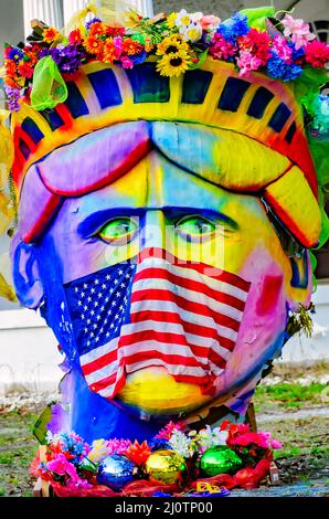 Ein Hausbesitzer macht eine politische Erklärung mit Mardi Gras Dekorationen mit der Freiheitsstatue, die eine amerikanische Flagge als Gesichtsmask und Schnauze trägt. Stockfoto