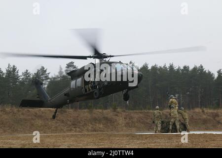 Luftangriffslehrer und Studenten führen Schlingentraglasoperationen mit UH-60 Blackhawk-Hubschraubern durch, die dem Bataillon 1st, dem Aviation Regiment 214th und dem Combat AVN 12th zugeordnet sind. Brigade, während des Luftansturzkurses der US-Armee im Trainingsgebiet Grafenwoehr, Deutschland, 27. Januar 2022. Das Combined Arms Training Center des Army Training Command 7th sponserte den zehntägigen Flugkurs, der von Ausbildern des Warrior Training Center der Army National Guard in Fort Benning, Georgia, angeboten wurde. Der Kurs schult Soldaten bei Luftangriffen, Schleuderbelastungen und Abseilen, um die Nutzung von h zu maximieren Stockfoto