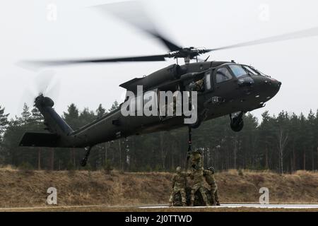 Luftangriffslehrer und Studenten führen Schlingentraglasoperationen mit UH-60 Blackhawk-Hubschraubern durch, die dem Bataillon 1st, dem Aviation Regiment 214th und dem Combat AVN 12th zugeordnet sind. Brigade, während des Luftansturzkurses der US-Armee im Trainingsgebiet Grafenwoehr, Deutschland, 27. Januar 2022. Das Combined Arms Training Center des Army Training Command 7th sponserte den zehntägigen Flugkurs, der von Ausbildern des Warrior Training Center der Army National Guard in Fort Benning, Georgia, angeboten wurde. Der Kurs schult Soldaten bei Luftangriffen, Schleuderbelastungen und Abseilen, um die Nutzung von h zu maximieren Stockfoto