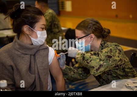 220128-N-SI601-1059 YOKOSUKA, Japan (Jan 28, 2022) Hospital Corpsman 3. Class Courtney Minchew, aus Ocala, Florida, der dem vorbereitenden Flugzeugträger der US-Marine USS Ronald Reagan (CVN 76) zugewiesen wurde, verwaltet einen COVID-19-Impfverstärker an einen japanischen Basismitarbeiter auf Commander, Fleet Activities Yokosuka. Ronald Reagan, das Flaggschiff der Carrier Strike Group 5, stellt eine kampfbereite Kraft zur Verfügung, die die Vereinigten Staaten schützt und verteidigt und Allianzen, Partnerschaften und kollektive maritime Interessen in der Indo-Pazifik-Region unterstützt. (USA Navy Foto von Mass Communication Specialist Stockfoto