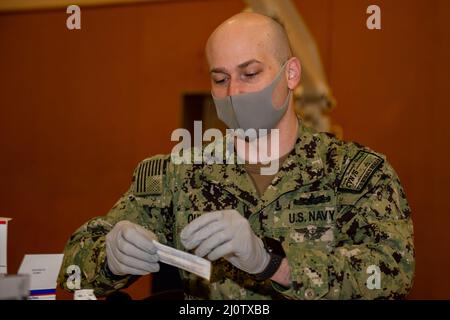 220128-N-SI601-1019 YOKOSUKA, Japan (Jan 28, 2022) Hospital Corpsman 2. Class Andrew Quigley aus Wichita, Kansa, der dem vorbereitenden Flugzeugträger der US-Marine USS Ronald Reagan (CVN 76) zugewiesen wurde, bereitet Bandagen für die Verabreichung von COVID-19 Impfverstärkern auf Commander, Fleet Activities Yokosuka vor. Ronald Reagan, das Flaggschiff der Carrier Strike Group 5, stellt eine kampfbereite Kraft zur Verfügung, die die Vereinigten Staaten schützt und verteidigt und Allianzen, Partnerschaften und kollektive maritime Interessen in der Indo-Pazifik-Region unterstützt. (USA Navy Foto von Mass Communication Specialist 3. CLA Stockfoto