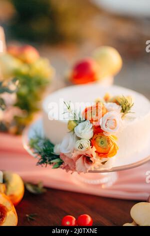 Weiße Hochzeitstorte mit Rosen geschmückt steht auf einem Tisch Stockfoto