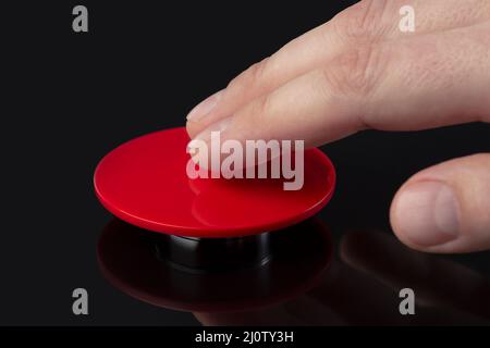 Die Hand drückt den großen roten Knopf. Das Konzept der Bedrohung durch einen Atomkrieg. Eine Bedrohung für die Welt mit einem nuklearen Koffer und einer Bombe. Die Hand Stockfoto