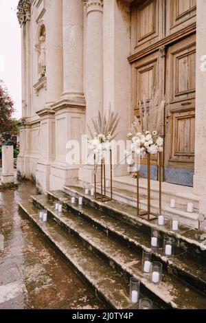 Blumensträuße stehen auf goldenen Metallpodesten auf den Stufen der Kirche Stockfoto