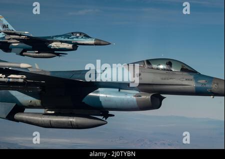 Zwei F-16C Kampffalken, die 64th Aggressor Squadron zugewiesen wurden, fliegen während einer Mission der Roten Flagge Nellis 22-1 am 28. Januar 2022 über den Nevada Test- und Trainingsbereich zurück in das Trainingsgebiet. Die 64th AGRS spielten als die Rote Kraft gegen die Blauen Kräfte in einem Training, das ‘First Timers’ Kampfmissionen priorisiert. (USA Air Force Foto von Tech. Sgt. Alexandre Montes) Stockfoto