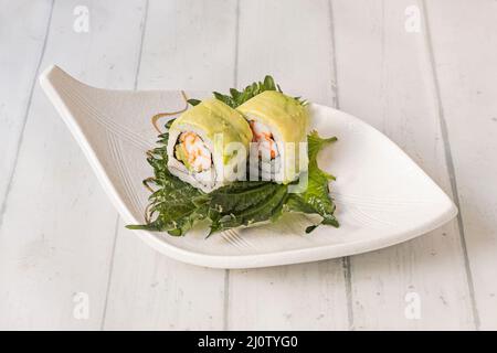 In Avocado gewickelte Brötchen, gefüllt mit Frischkäse und Schnittlauch und mehr auf einem Shiso-Blatt Stockfoto