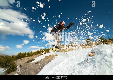 Stilvolle junge Mädchen Snowboarder tut den Trick in Springen aus einem Schneekicker gegen den blauen Himmel Wolken und Berge in der spr Stockfoto