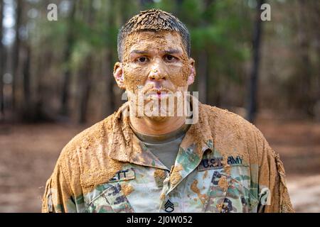 Personal Sgt. Andrew Barnett, 2. Brigade, 98. Training Division (Initial Entry Training), nachdem er am 28. Januar 2022 im Hindernisparcours im Rahmen des 2022 Best Warrior Competition der 98. Training Division in Fort Benning, Georgia, aus dem Schlamm gekrochen war. Der Best Warrior Competition würdigt Soldaten, die sich für die Werte der Armee einsetzen, den Warrior Ethos verkörpern und die Macht der Zukunft repräsentieren. (USA Army Reserve Foto von Sgt. Jeffery Harris) Stockfoto