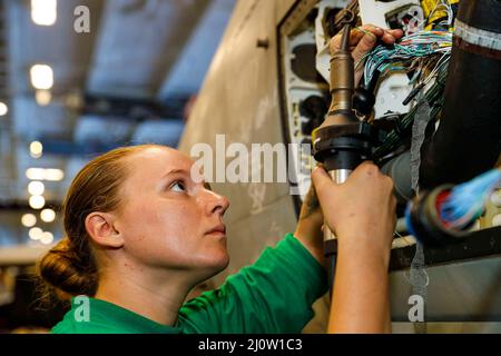 Philippinische See. 13. März 2022. Aviation Electronics Technician 3. Klasse Lillian Phipps, aus Hardinsburg, Ind., beauftragt mit dem Black Aces of Strike Fighter Squadron (VFA) 41, führt Wartungsarbeiten an einem F/A-18F Super Hornet in der Hangarbucht an Bord des Flugzeugträgers USS Abraham Lincoln (CVN 72) der Nimitz-Klasse durch. Die Abraham Lincoln Strike Group befindet sich im geplanten Einsatzgebiet der US-Flotte für 7., um die Interoperabilität durch Allianzen und Partnerschaften zu verbessern und gleichzeitig als reaktionsfähige Truppe zur Unterstützung einer freien und offenen Region im Indo-Pazifik-Raum zu dienen. (Bild: © U.S. Navy/Z Stockfoto