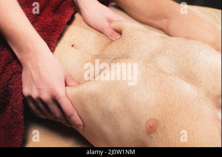 Professionelle Massage des Zwerchfells mit einem Mann in einem professionellen Massageraum aus nächster Nähe. Das Konzept der inneren Organe und der Abdomung Stockfoto