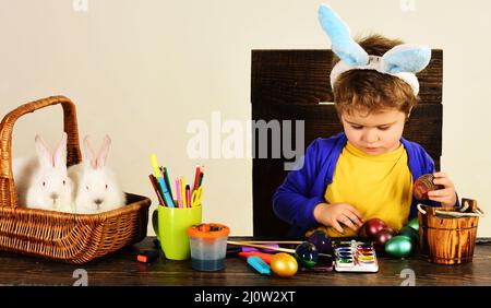 Kind hält Korb mit bemalten Eiern. Hasenohren und Hasenohren. Stockfoto