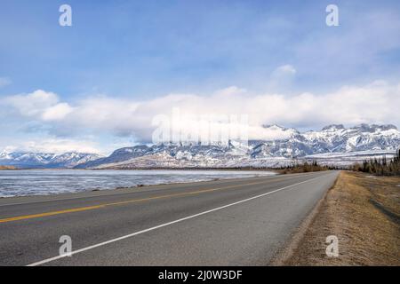 Ein flacher, gerader Highway mit 2 Fahrspuren im Jasper National Park, der zu schneebedeckten Bergen führt Stockfoto