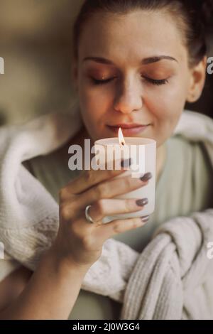 Junge, ruhige, friedliche Frau mit brennender Kerze und riechendem Aroma Stockfoto