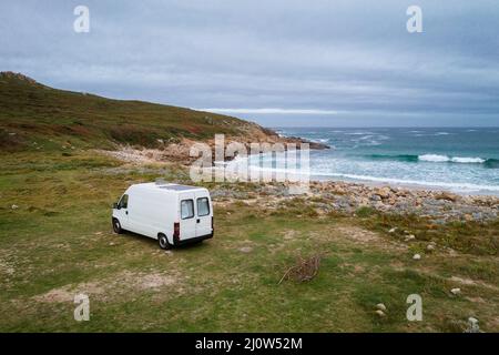 Drohne Luftaufnahme eines Wohnwagens an einem wilden Strand mit grüner Landschaft in Galicien, Spanien Stockfoto