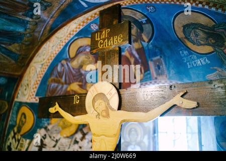 Hölzernes Kruzifix in einer orthodoxen Kirche in der Nähe einer gewölbten Fensteröffnung Stockfoto