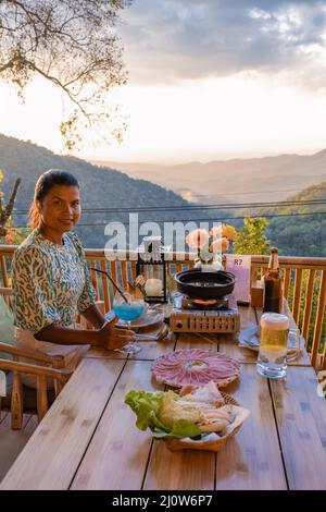 Abendessen in den Bergen von Chiang Mai Thailand, Tisch bbq, Asian Mann mit Küchenzangen grillen Rindfleisch und Speck auf Grillplatte. Stockfoto