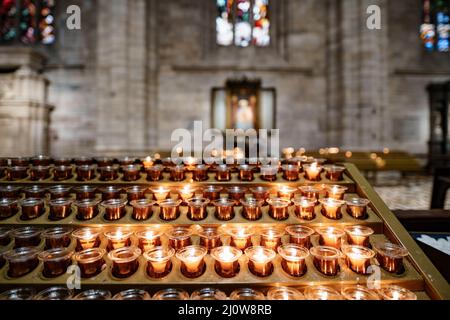 Votivkerzen brennen auf einem Ständer im Dom. Nahaufnahme Stockfoto