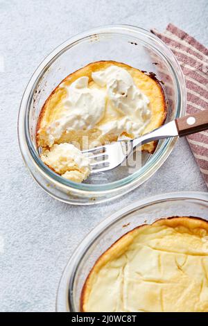 Köstlicher Quark-Auflauf in portionierten Glasformen mit Sauerrahm. Traditionelle russische Küche zum Frühstück - Zapekan Stockfoto