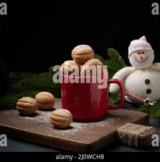 Gebackenes, nussförmiges Dessert in einem roten Keramikbecher, bestreut mit Puderzucker Stockfoto