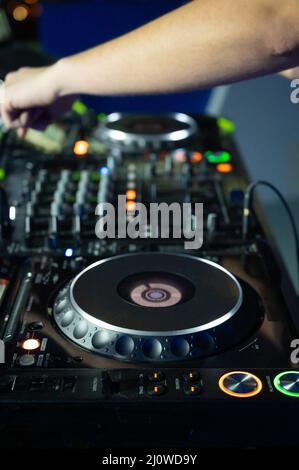 Nahaufnahme des DJ Mixer Controller Desk bei der Night Club Disco Party. DJ Hände berühren Tasten und Schieberegler spielen elektronische Musik . Stockfoto