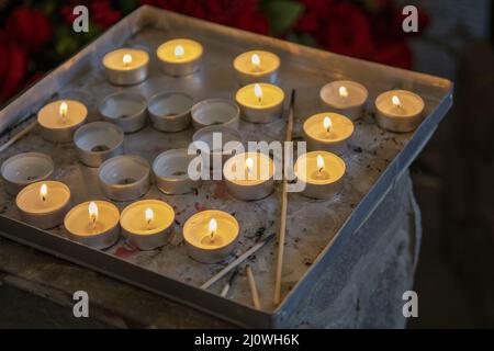 Brennende Gebetskerzen in einer katholischen Kirche. Beleuchtete Teelichter. Selektiver Fokus. Stockfoto