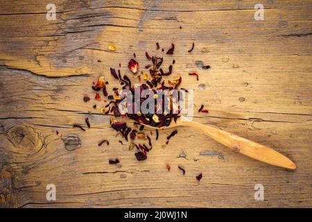 Holzlöffel mit getrocknetem Blumentee auf einem alten hölzernen Hintergrund Draufsicht Stockfoto