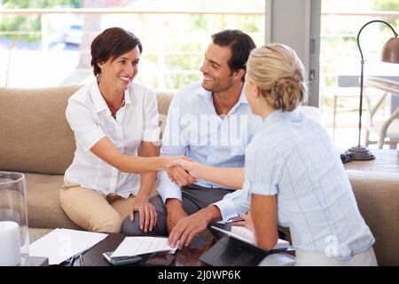 Er hilft ihnen dabei, kluge finanzielle Entscheidungen zu treffen. Aufnahme eines Paares, das sich zu Hause mit seinem Finanzberater trifft. Stockfoto