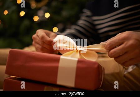 Den Knoten zu Weihnachten binden. Aufnahme eines hübschen jungen Mannes, der sich auf Weihnachten vorbereitet. Stockfoto