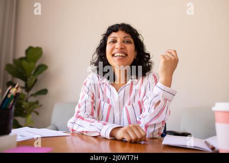 Porträt einer lächelnden jungen Geschäftsfrau, die im Büro am Schreibtisch sitzt Stockfoto