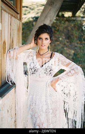 Mädchen in einem weißen Kleid steht mit ihrem Ellbogen auf einer Holzwand Stockfoto