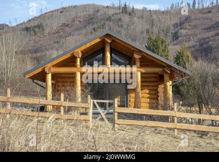 Traditionelles Holzhaus auf der Wiese im Winter. Stockfoto