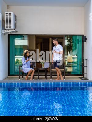 Ein Paar, ein Mann und eine Frau trinken eine Tasse Kaffee vor der Wohnung in Thailand, eine asiatische Frau und ein europäischer Mann in Fr. Stockfoto