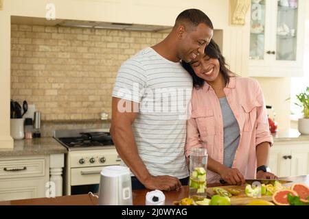 Glückliches junges afroamerikanisches Paar, das zusammen in der Küche zu Hause Essen zubereitet Stockfoto