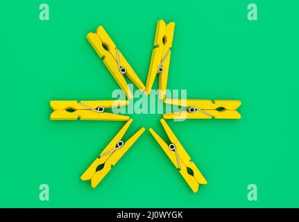 Gelbe bunte Holzkleidernadeln auf grünem Hintergrund Stockfoto