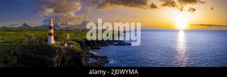 Panoramablick auf den Sonnenuntergang über der Küste und dem Leuchtturm auf einer Insel Stockfoto