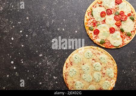 Fast Food, gebackene Tiefkühlpizza mit vier Käsesorten und Pizza mit Mozzarella-Käse, Tomaten und Pesto. Bereit zum Essen Stockfoto