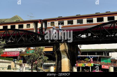 Kanchanaburi, Thailand. 21.. Februar 2022. Ein Tourist macht Fotos, während ein Personenzug die Brücke am Fluss Kwai überquert, der etwa 140 km westlich der Hauptstadt Bangkok liegt. Gebaut von den Japanern, um eine Route zwischen Thailand und Myanmar zu schaffen, die als Todesbahn bekannt ist. Über 60.000 alliierte Gefangene bauten die Brücke während der japanischen Besetzung Thailands, 13,000 Gefangene kamen während des Baus ums Leben. Die im Oktober 1943 fertiggestellte Eisenbahnlinie verbindet die südliche Hauptlinie Thailands von Bangkok aus. (Bild: © Paul Lakatos/SOPA Images via ZUMA Press Wire) Stockfoto
