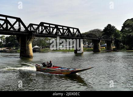 Kanchanaburi, Thailand. 21.. Februar 2022. Ein thailändisches Langschwanz-Boot passiert die Brücke auf dem Fluss Kwai, etwa 140 km westlich der Hauptstadt Bangkok. Gebaut von den Japanern, um eine Route zwischen Thailand und Myanmar zu schaffen, die als Todesbahn bekannt ist. Über 60.000 alliierte Gefangene bauten die Brücke während der japanischen Besetzung Thailands, 13,000 Gefangene kamen während des Baus ums Leben. Die im Oktober 1943 fertiggestellte Eisenbahnlinie verbindet die südliche Hauptlinie Thailands von Bangkok aus. (Bild: © Paul Lakatos/SOPA Images via ZUMA Press Wire) Stockfoto