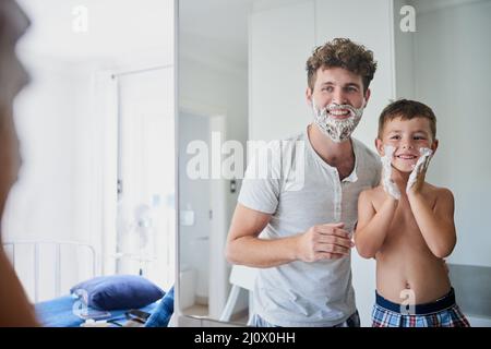 Mache ich es richtig, Papa. Aufnahme eines Vaters, der seinem kleinen Sohn beibringt, sich im Badezimmer zu Hause zu rasieren. Stockfoto